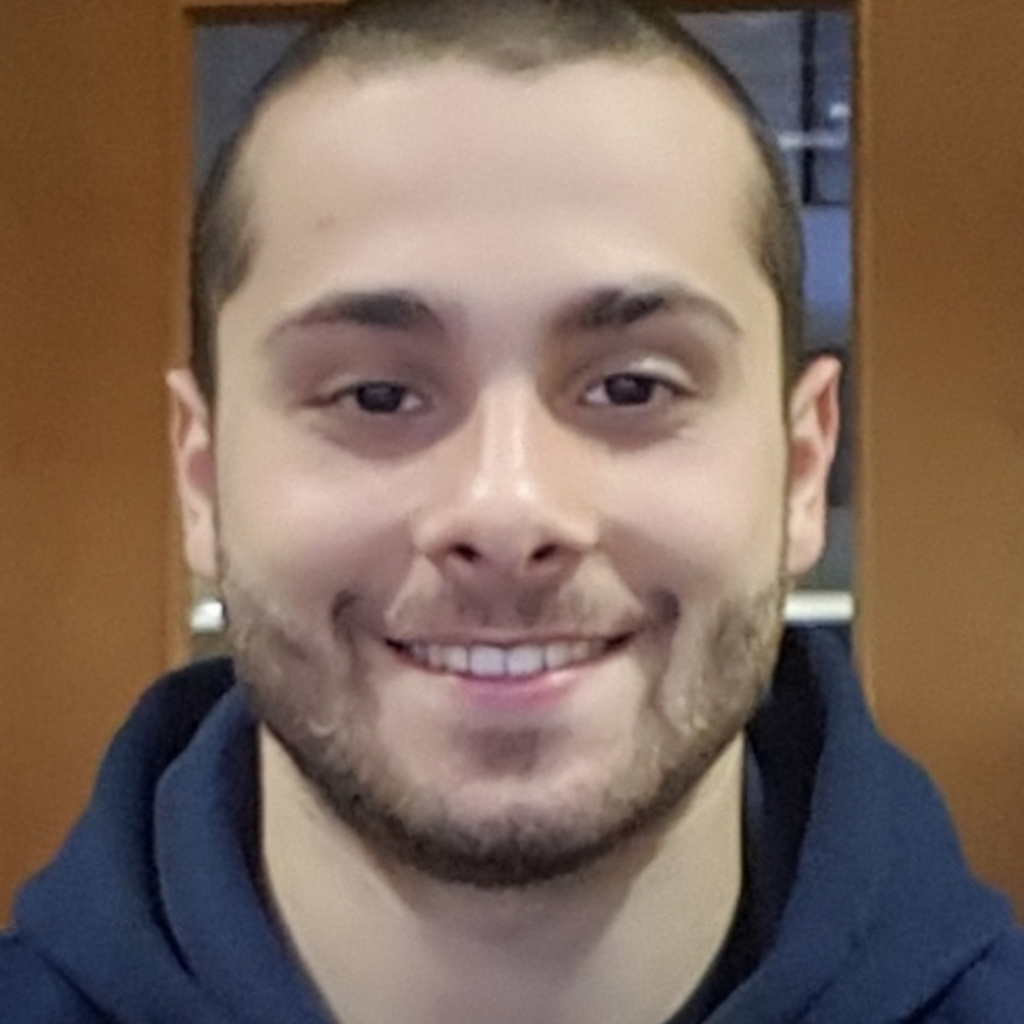 A young man smiles at the camera