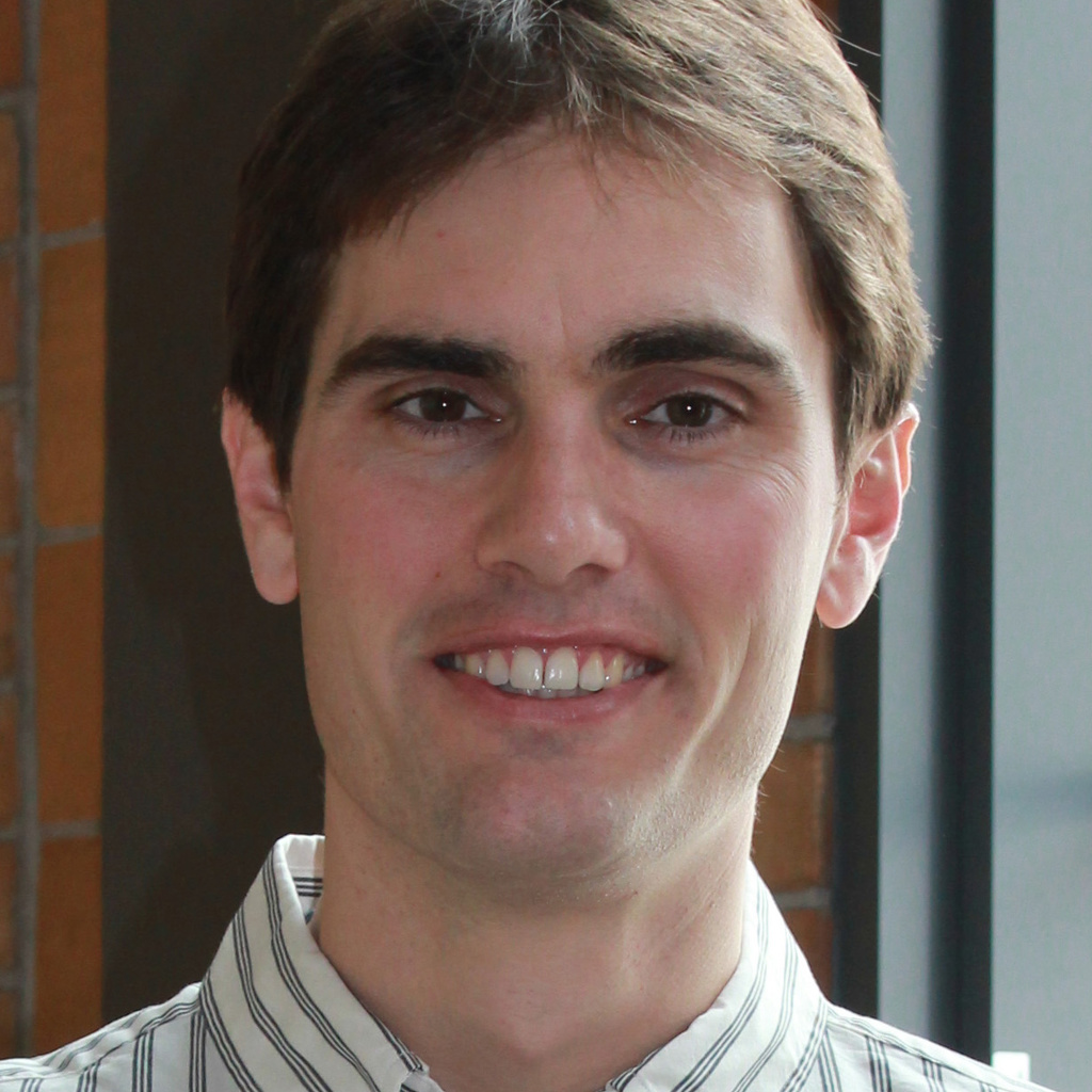 A young man smiles at the camera